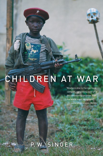 Book cover for Children at War. Photo extends to all edges. A young boy soldier in a red beret and red shorts stands in a grassy field holding an assault rifle. A painted human skull atop a wooden post stands in the background. Text is white.